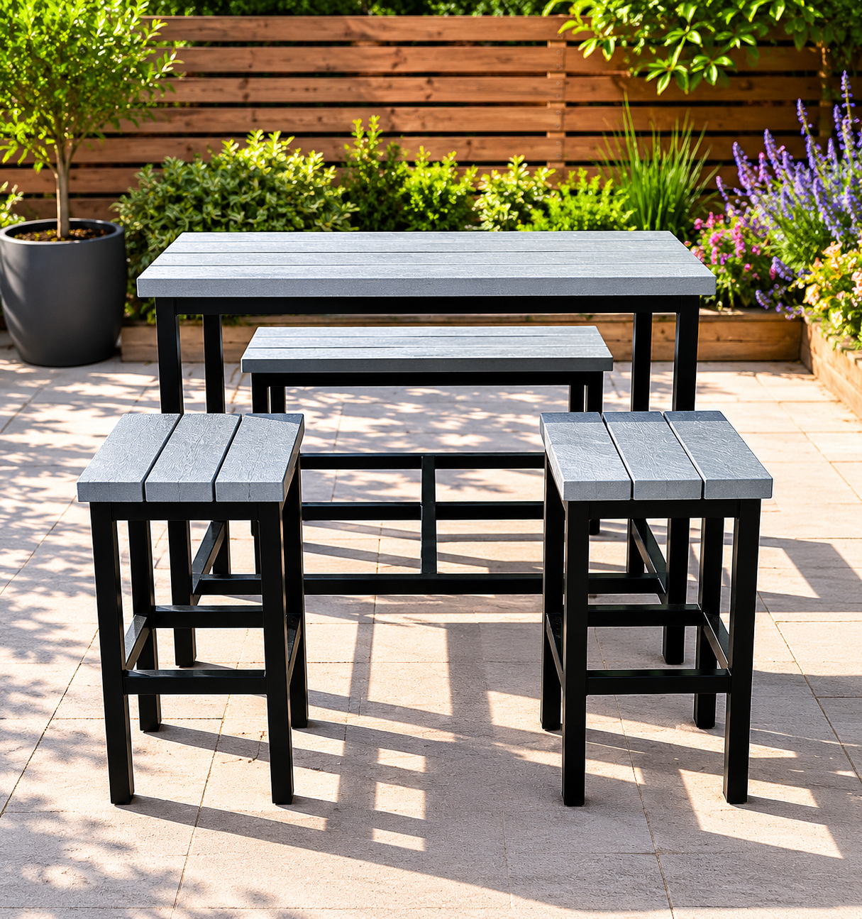 Outdoor metal patio dining set: a blue-gray rectangular table with matching benches and stools on a tiled patio, with greenery and a wooden fence in the background