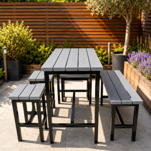 Outdoor metal dining set with a gray slatted table and matching benches on a paved patio with greenery nearby.